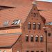 Red brick facade of a historic building in Gdańsk, Poland with intricate roof design.